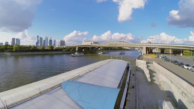 Several vessels with tourists sail by river near transport bridge
