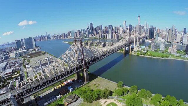 Cars drive by Queensboro Bridge over East River at summer