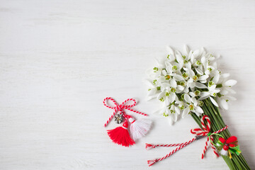 White wooden background with a bouquet of snowdrop flowers and red and white martenitsa for the holiday of March 1, copy space. - 711039161