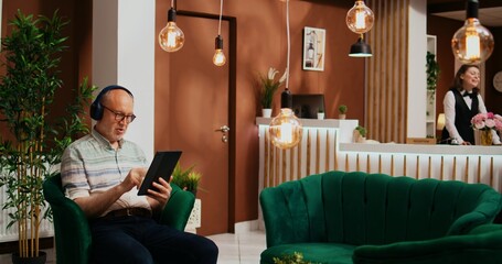 Tourist having fun with gadget at hotel, watching film or tv show before doing check in at...