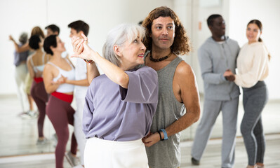 Fototapeta na wymiar Adult couples of dancers, engaged in a dance studio, studying salsa in lesson