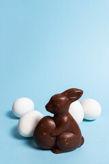 Easter chocolate bunny and white eggs on a blue background