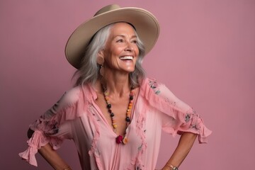Portrait of a happy senior woman in hat posing on pink background