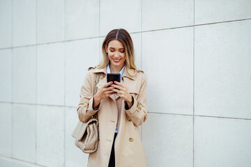 Businesswoman holding her phone outside a large building.