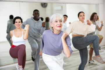 Energetic elderly lady attending group choreography class, learning modern dynamic dances. Concept...