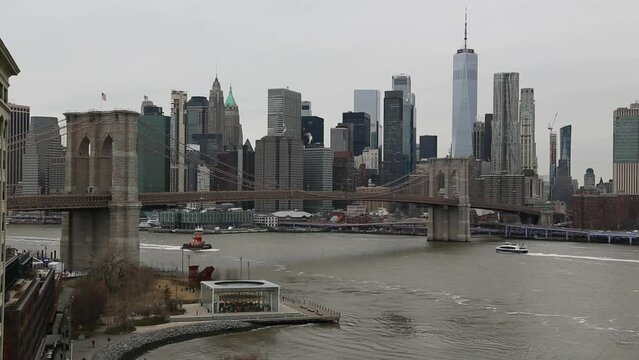nyc skyline view with water moving on a gray overcast sky day (ferries on the water, view from manhattan bridge, dumbo carousel) downtown footage with one world trade center, brooklyn bridge 