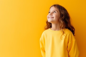 Portrait of a cute little girl in a yellow sweatshirt on a yellow background