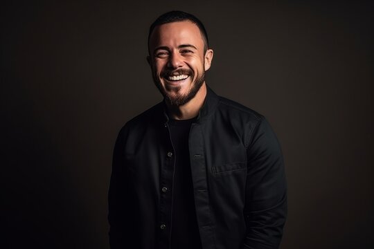 Portrait of a handsome young man laughing and looking at the camera on a dark background