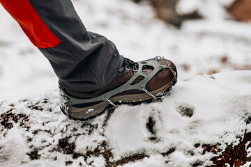 Close up of a boot with crampons on a winter mountain trail