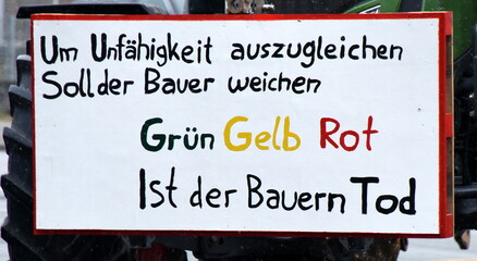 Transparent auf einem Traktor: "Um Unfähigkeit auszugleichen soll der Bauer weichen. Grün Gelb Rot ist der Bauern Tod."