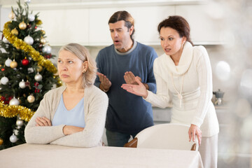 Woman and man swear at old mother who puts up with it at christmas while sitting at kitchen table