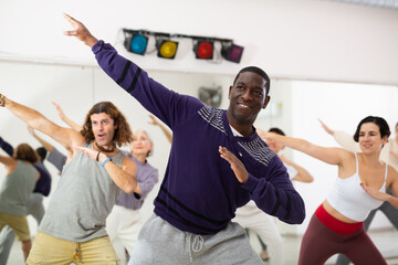 African-american guy practising dance moves with other people in dance studio