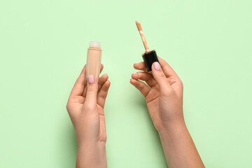 Female hands with bottle of liquid makeup foundation on color background, closeup