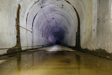 Naklejka premium Dark flooded dirty tunnel at old underground bunker