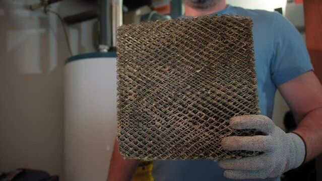 Worker HVAC services changing a folded dirty air filter in the HVAC furnace system in home. Close up