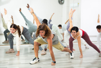 Caucasian man rehearsing modern dance with group in dance school