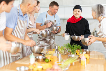 Group of happy people and female chef at cooking classes