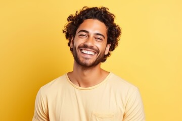 Portrait of a happy young latin man over yellow background.