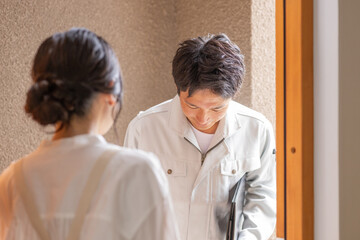 自宅を訪問する作業服姿の男性ビジネスマン（住まい・建築・修理）
