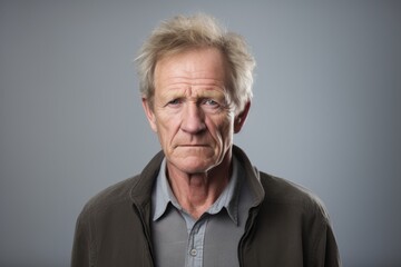 Portrait of senior man with serious expression, over grey background.