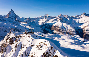 Picturesque winter Alpine landscape of snow-capped rocky ridge Gornergrat with observatory on...