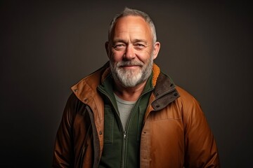 Portrait of a senior man with a gray beard wearing a brown jacket.