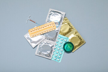 Contraceptive pills, condoms and intrauterine device on light grey background, flat lay. Different birth control methods