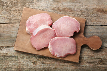 Pieces of raw pork meat on wooden table, top view