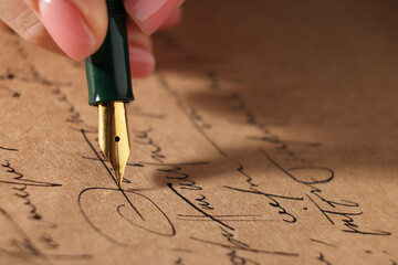 Fototapeta premium Woman writing letter with fountain pen, closeup