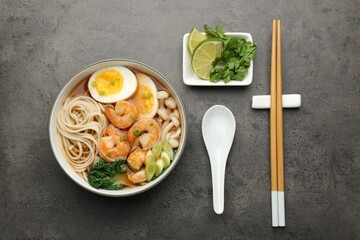 Delicious ramen with shrimps and egg in bowl served on grey table, flat lay. Noodle soup