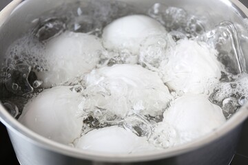Chicken eggs boiling in saucepan, closeup view