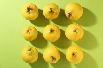 Naklejka na ściany i meble Tasty ripe quinces on light green background, flat lay