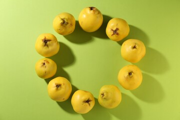 Frame made of tasty ripe quinces on light green background, flat lay. Space for text
