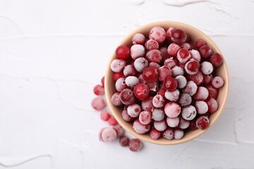 Frozen red cranberries in bowl on white table, top view. Space for text