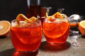 Aperol spritz cocktail, ice cubes and orange slices in glasses on grey textured table, closeup