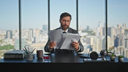 Stressed professional throwing papers in cityscape office. Upset man thinking