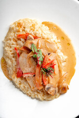 Stewed chicken with sauce, mushrooms, paprika and rice in a white plate, top view