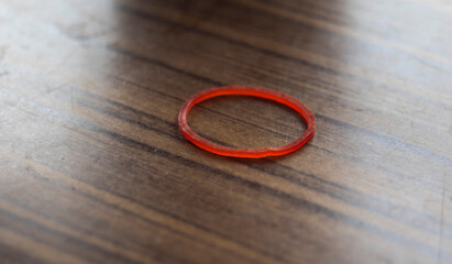 Red rubber ring on a wooden background, close-up - obrazy, fototapety, plakaty