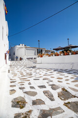 Streetview of Mykonos town with white street and blue door, Greece