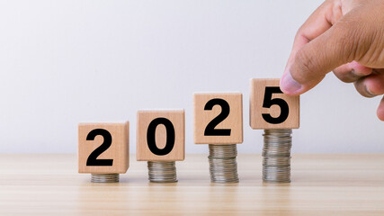 2025 text on wooden cube block with arranging stack of coin. planning, investment, savings ,...