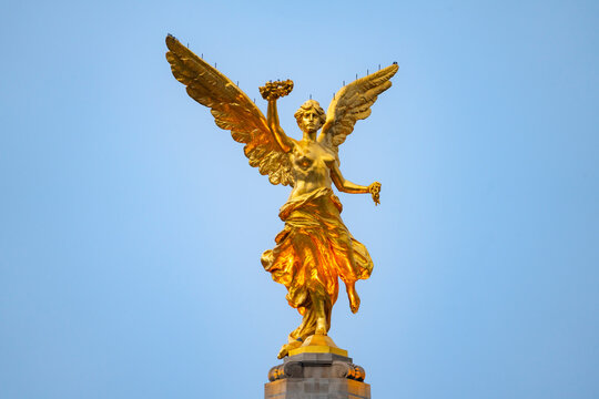 The Angel of Independence statue placed on Promenade of the Reform in Mexico city between tall skyscrapers against midday