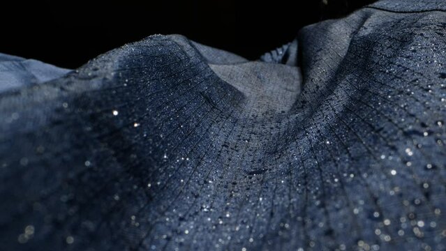 Waterproof clothing for tourism. Blue cloth texture with water drop close-up macro. Repellent waterproof breathable fabrics. Innovation waterproofing material test