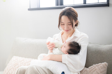 Woman sitting on the sofa feeding her baby, cute and very precious.