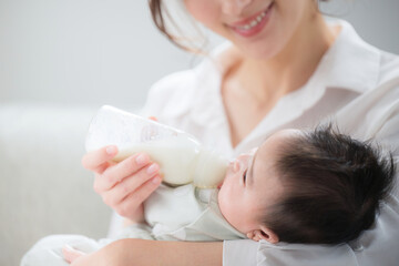 Obraz na płótnie Canvas 赤ちゃんにミルクをあげる女性　顔無し