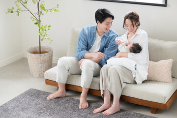 Family of three relaxing in the living room, baby and young couple's whole body.