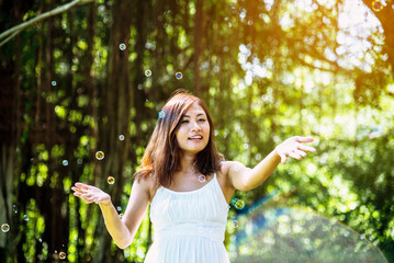 Happy Relax beautiful asian woman smiling face standing in green park outdoors garden. Young women enjoy nature morning Freedom Lifestyle. woman breathing fresh air and relax breath in green park - obrazy, fototapety, plakaty