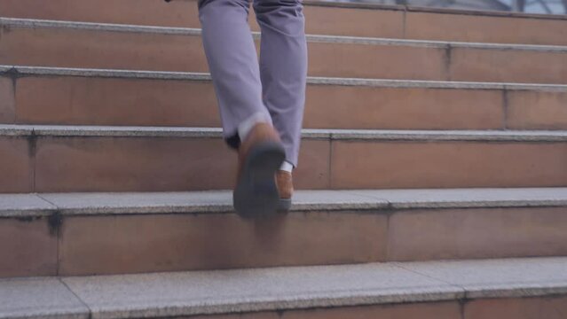 Close up shot of hurry Asian young businessman running up on stair going to work in office. 