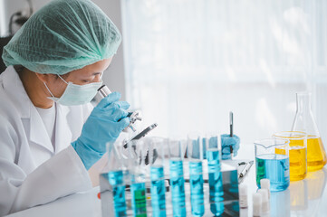 Female researchers are experimenting with pipette dropping a sample into a test tube in an experiment research in laboratory...