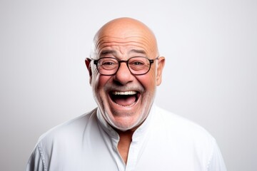 Portrait of a senior man with glasses laughing on a gray background
