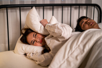 Asian woman feel frustrated from husband snoring while sleep at night. 